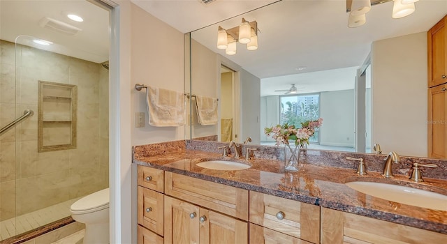 bathroom featuring ceiling fan, toilet, vanity, and a tile shower