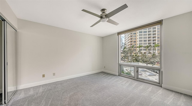 unfurnished bedroom featuring ceiling fan, light colored carpet, a closet, and expansive windows