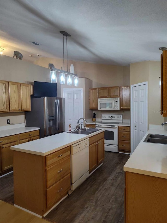 kitchen with white appliances, decorative light fixtures, a center island with sink, and sink