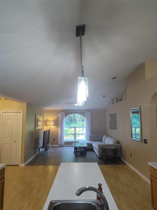 kitchen featuring sink, decorative light fixtures, vaulted ceiling, and dark hardwood / wood-style floors