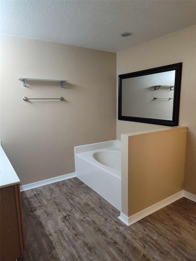 bathroom with a tub, a textured ceiling, hardwood / wood-style flooring, and vanity