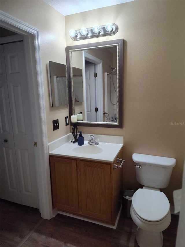 bathroom featuring toilet, vanity, and hardwood / wood-style floors