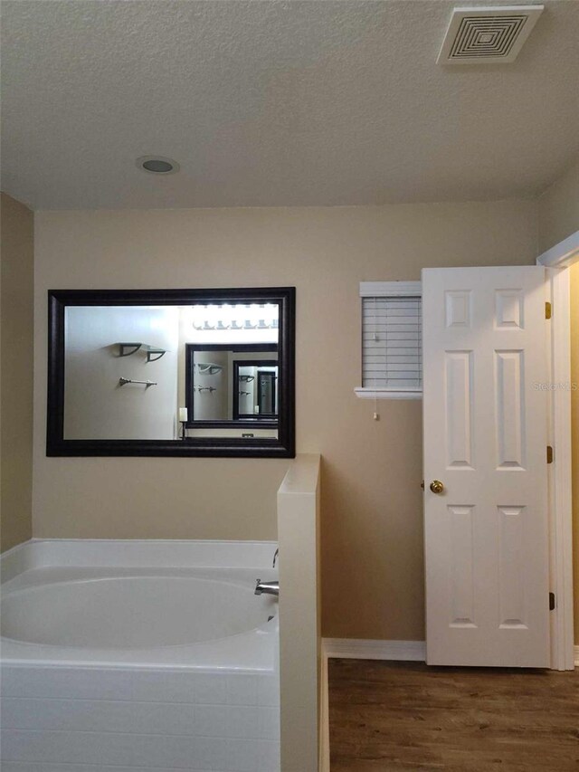 15900 SW 19th Avenue Rd, Ocala, FL 34473 - bathroom featuring wood finished floors, a bath, and a textured ceiling