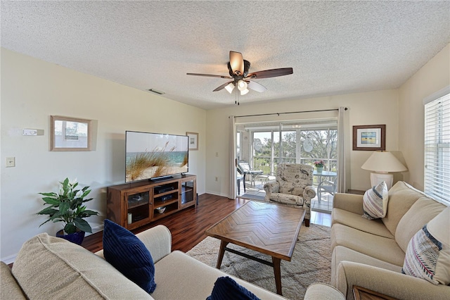 living room featuring ceiling fan, dark hardwood / wood-style flooring, and a textured ceiling