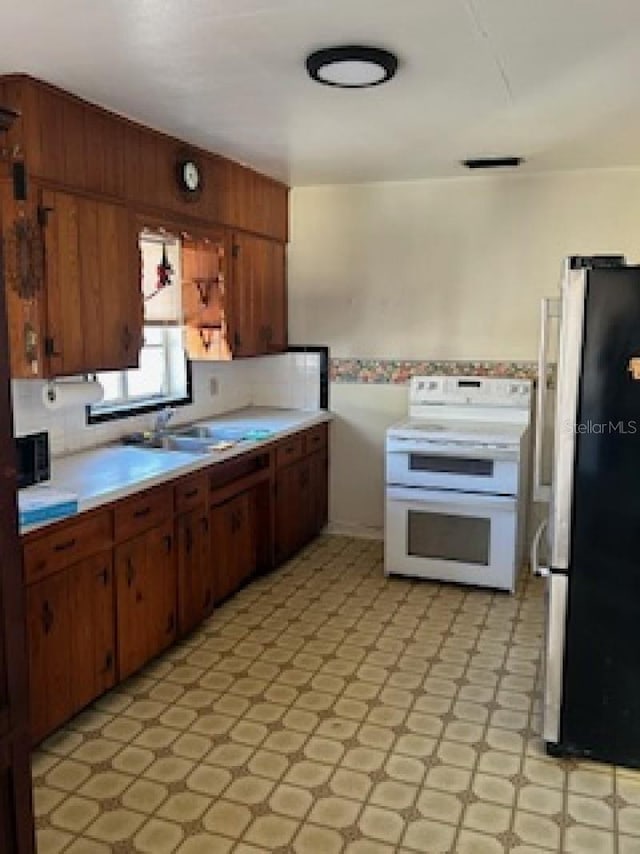 kitchen featuring stainless steel refrigerator, decorative backsplash, double oven range, and sink