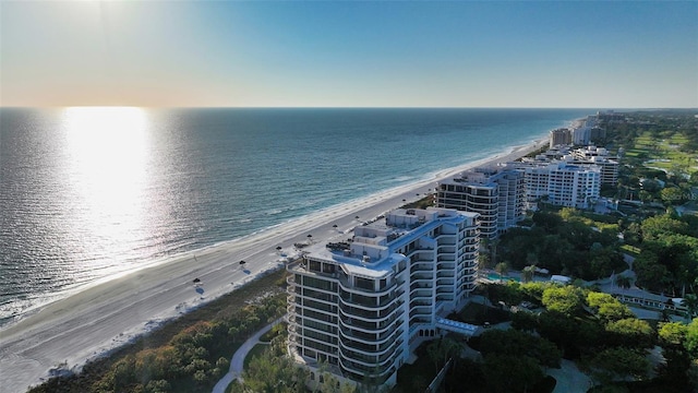 aerial view at dusk with a water view and a view of the beach