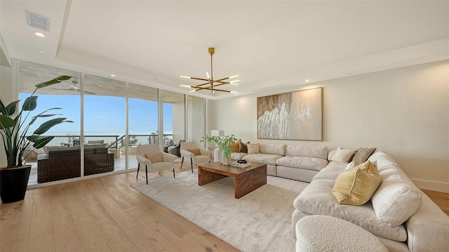 living room with a water view, a wall of windows, a chandelier, and light hardwood / wood-style floors