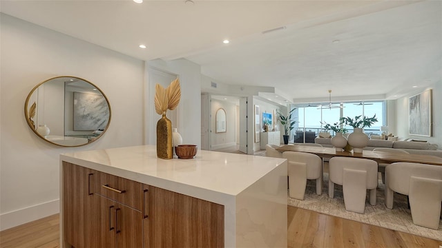 kitchen with an inviting chandelier, a kitchen island, and light hardwood / wood-style flooring