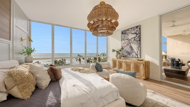 bedroom featuring multiple windows, light hardwood / wood-style flooring, and a water view