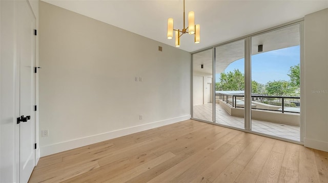 empty room featuring light hardwood / wood-style floors, expansive windows, and an inviting chandelier