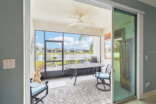 sunroom with ceiling fan and a water view