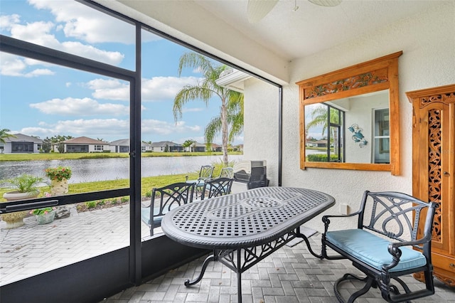 sunroom with ceiling fan, a healthy amount of sunlight, and a water view