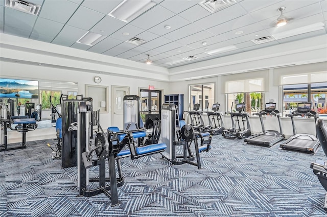 gym with a paneled ceiling, a towering ceiling, and carpet flooring