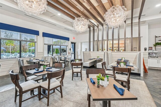 dining room featuring a towering ceiling, a notable chandelier, and beamed ceiling