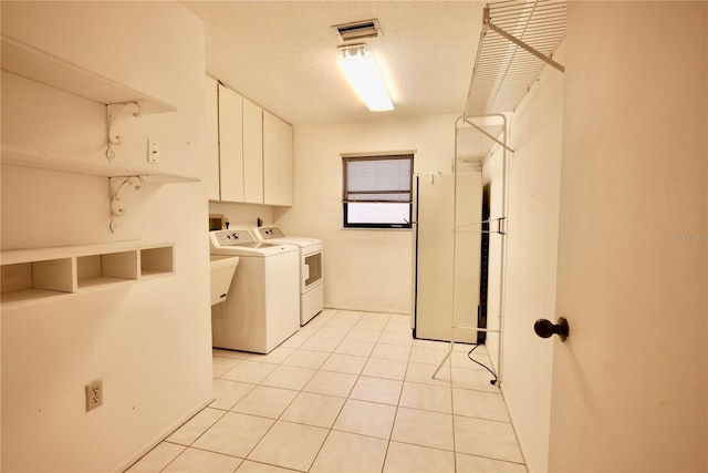 laundry room with cabinets, separate washer and dryer, a textured ceiling, and light tile patterned flooring