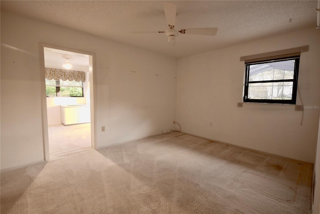 unfurnished room with ceiling fan, a textured ceiling, and light carpet