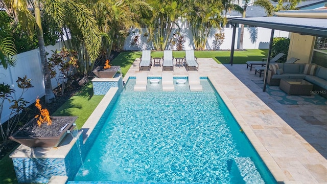 view of swimming pool with a yard, a patio area, a hot tub, an outdoor living space with a fire pit, and pool water feature