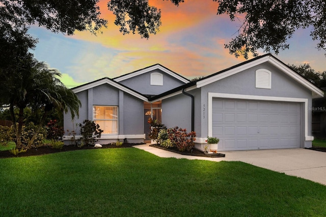 ranch-style home featuring a lawn and a garage