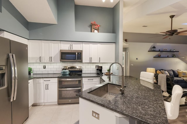 kitchen with dark stone countertops, white cabinetry, appliances with stainless steel finishes, ceiling fan, and sink