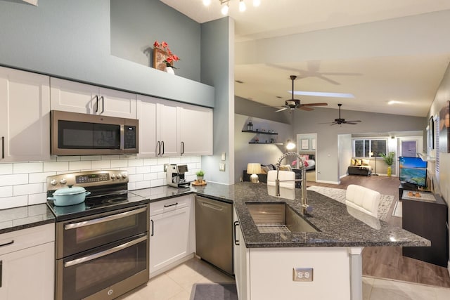 kitchen with appliances with stainless steel finishes, kitchen peninsula, ceiling fan, white cabinets, and sink