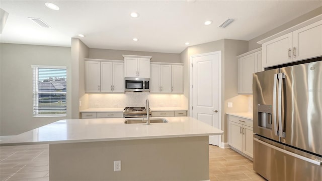 kitchen featuring stainless steel appliances, white cabinetry, sink, and a kitchen island with sink