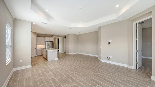 unfurnished living room with light hardwood / wood-style flooring and a raised ceiling