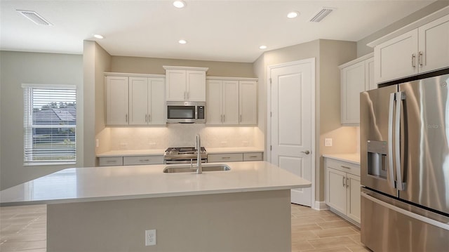 kitchen with stainless steel appliances, white cabinets, and a kitchen island with sink