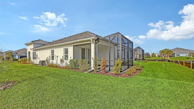 rear view of house with central AC, a lanai, and a yard