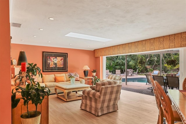 living room with light wood-type flooring and a skylight