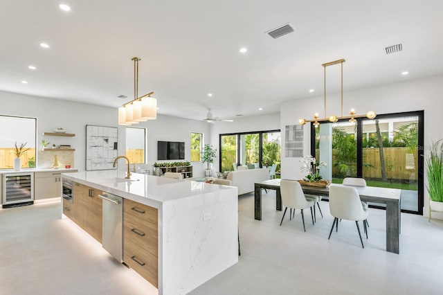 kitchen with beverage cooler, ceiling fan, pendant lighting, light stone counters, and a spacious island