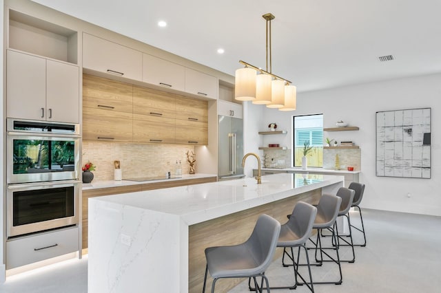 kitchen with light stone counters, pendant lighting, a breakfast bar area, a kitchen island with sink, and appliances with stainless steel finishes