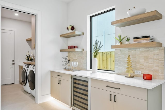 bar with light stone counters, independent washer and dryer, wine cooler, and tasteful backsplash