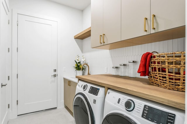 clothes washing area with washer and clothes dryer and cabinets