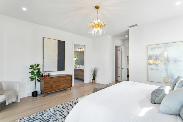 bedroom with sink, ensuite bathroom, an inviting chandelier, and hardwood / wood-style floors