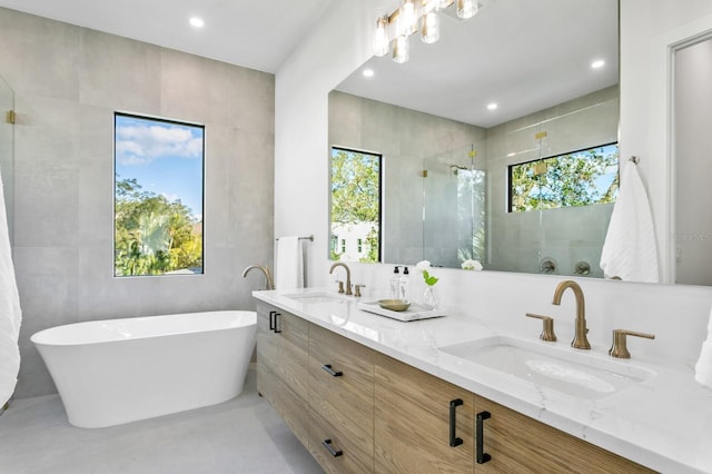 bathroom with tile walls, separate shower and tub, and vanity