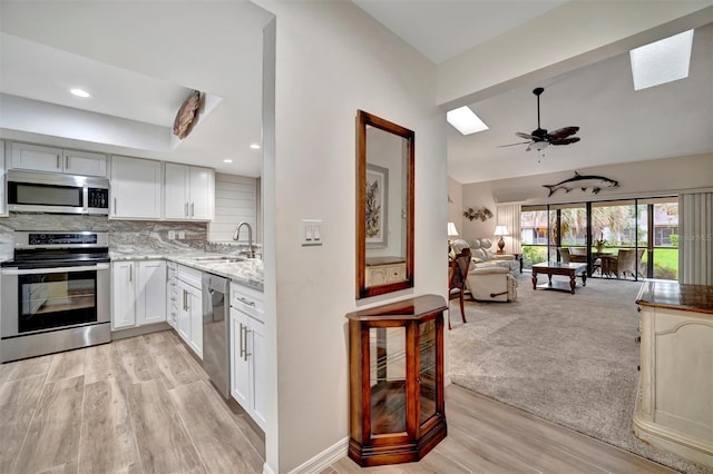 kitchen with light carpet, sink, white cabinets, tasteful backsplash, and stainless steel appliances