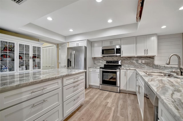 kitchen featuring sink, white cabinetry, a tray ceiling, and appliances with stainless steel finishes