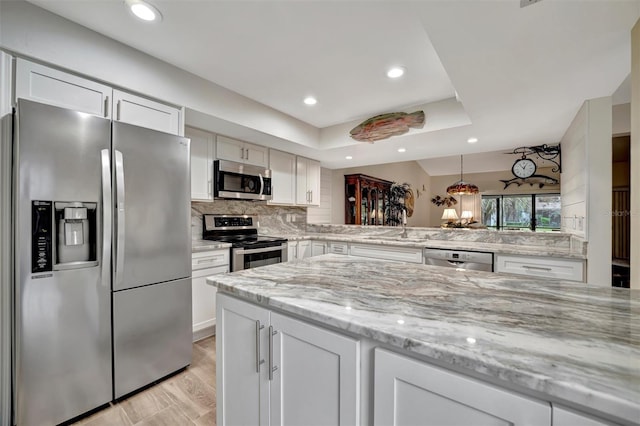 kitchen with sink, tasteful backsplash, white cabinetry, light stone counters, and stainless steel appliances