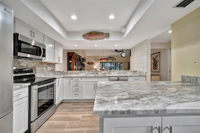 kitchen with kitchen peninsula, sink, white cabinetry, and stainless steel appliances