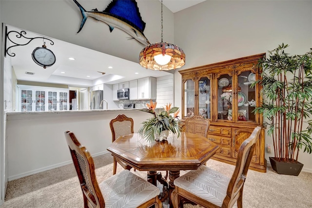 dining area featuring a tray ceiling and light carpet