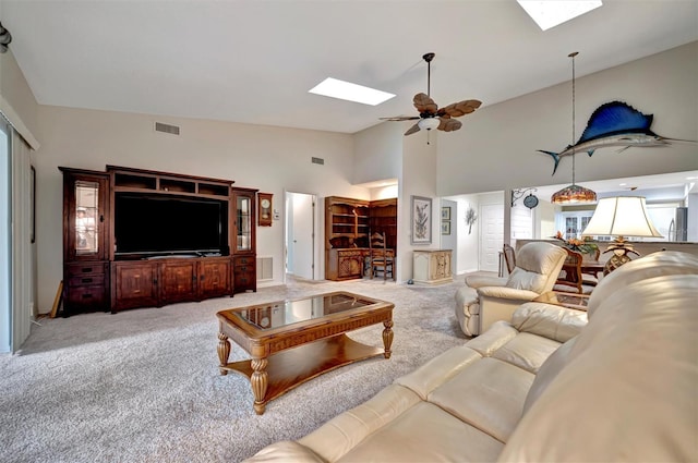 carpeted living room with ceiling fan and vaulted ceiling with skylight