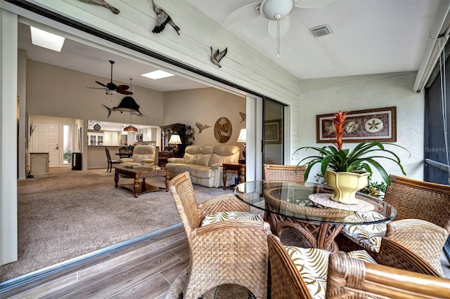 carpeted dining room featuring ceiling fan and vaulted ceiling with skylight