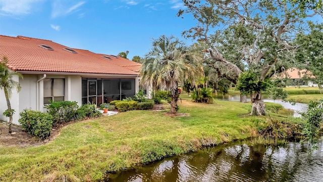 view of yard featuring a sunroom and a water view