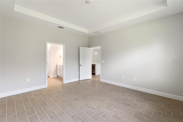 unfurnished bedroom featuring connected bathroom and a raised ceiling