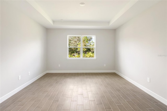 empty room with a raised ceiling and hardwood / wood-style floors