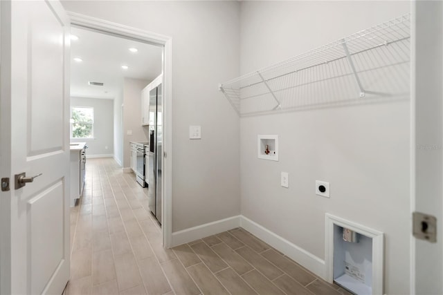 laundry room featuring electric dryer hookup, washer hookup, and light hardwood / wood-style floors