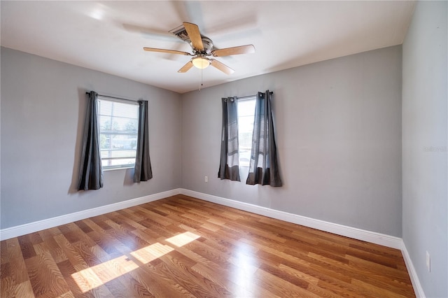 spare room with a wealth of natural light, ceiling fan, and light wood-type flooring