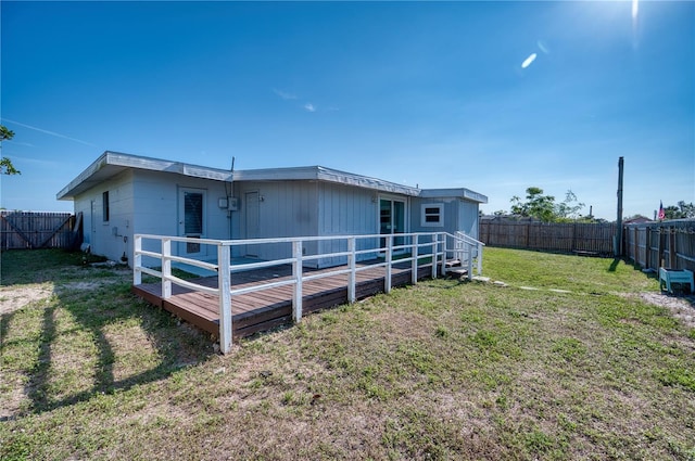 back of house with a wooden deck and a lawn