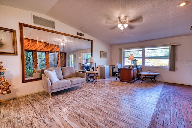 living room with hardwood / wood-style flooring, ceiling fan, vaulted ceiling, and a textured ceiling