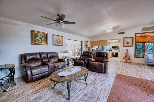 living room featuring ceiling fan, lofted ceiling, light hardwood / wood-style floors, and a textured ceiling